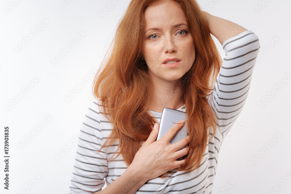 Upset ginger-haired woman pressing phone to her chest Upset ginger-haired woman pressing phone to her chest