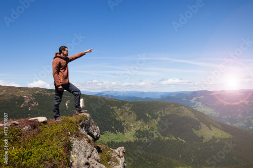 Man standing on the mountain top and pointing on horizon