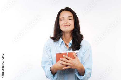 Happy young woman pressing gift box to her chest