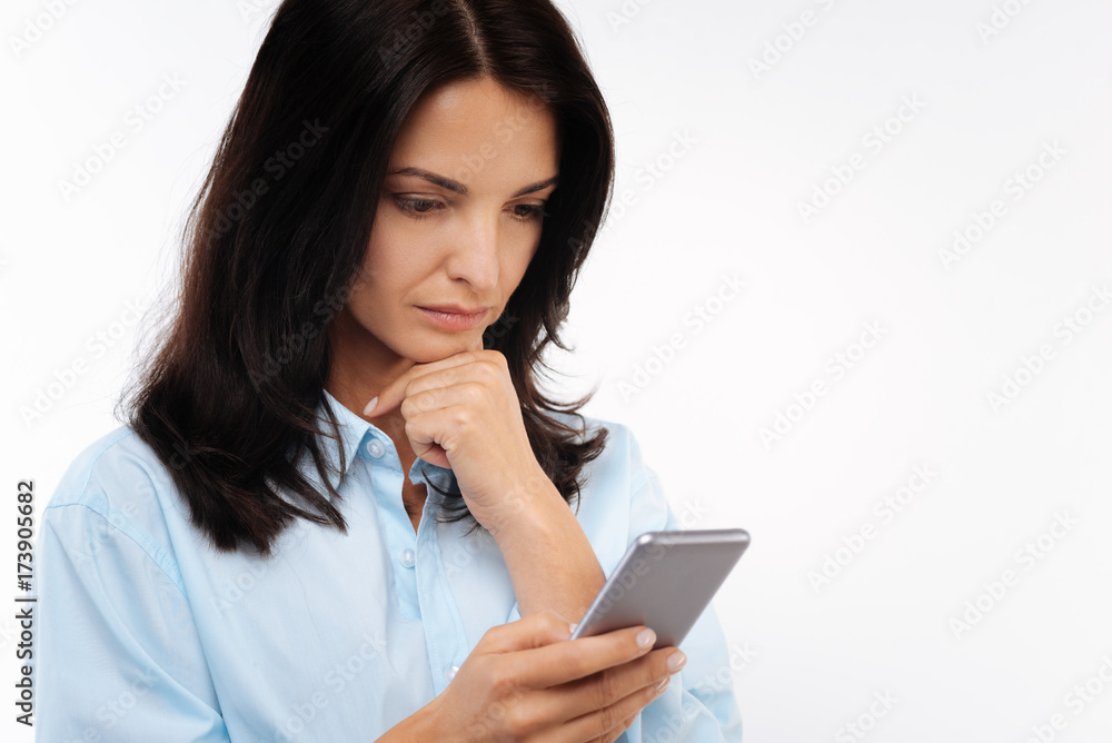 Serious woman reading newsfeed on phone Serious woman reading newsfeed on phone