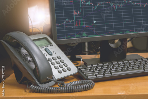 IP telephone with computer keyboard and monitor display financial chart on screen