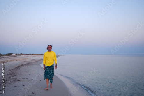 Smiling man traveler is walking along the surf line