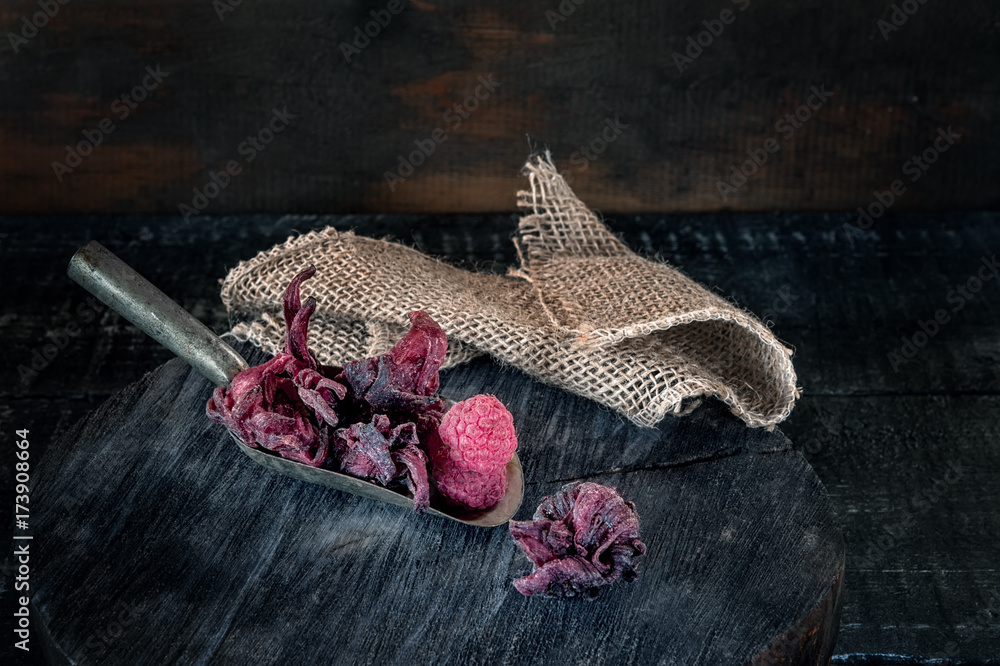 Sweet dried syrup hibiscus flowers with ripe raspberries in the scoop. Copy space. Sweet dried syrup hibiscus flowers with ripe raspberries in the scoop. Copy space.