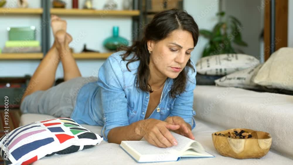 Woman in denim shirt looks bored while reading book on the sofa
Woman in denim shirt looks bored while reading book on the sofa