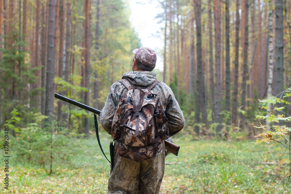 hunter with shotgun walking in the forest