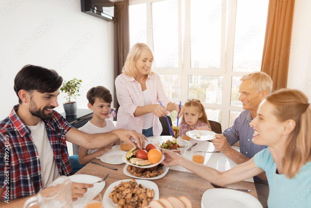 The family gathered for a festive dinner for Thanksgiving. Everyone puts food in plates The family gathered for a festive dinner for Thanksgiving. Everyone puts food in plates