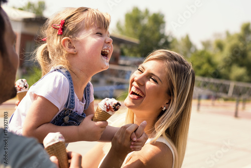 Parents and daughter eating ice cream and having fun outside