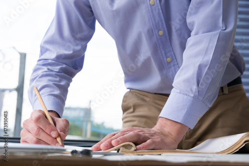 architect working on construction plan at office. engineer inspect blueprint at workplace. man sketching real estate project. drawing compass, vernier caliper on desk.