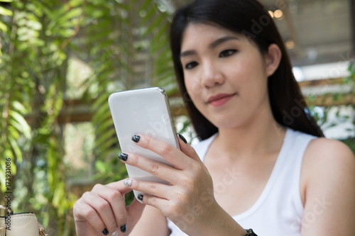 asian woman sit at outdoor cafe. young female adult use mobile phone at coffee shop. attractive teenager connect online network communication on smart phone. technology, lifestyle concept