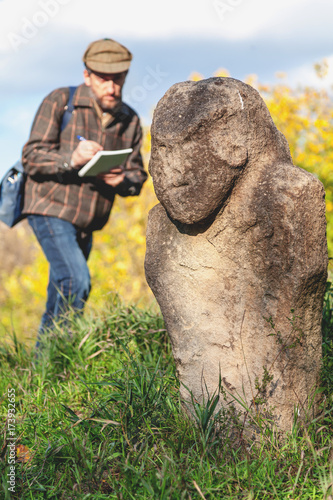 Scientific historian describes stone sculpture on mound © glebchik