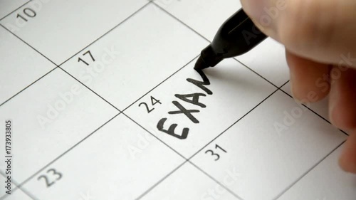Writing EXAM on calendar with a black marker