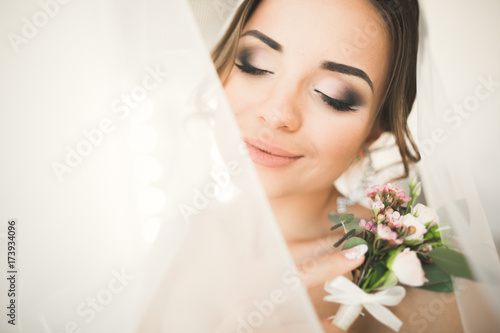 Gorgeous bride in robe posing and preparing for the wedding ceremony face in a room