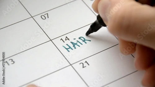 Writing HAIRCUT on calendar with a green marker