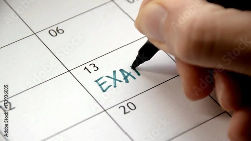 Writing EXAM on calendar with a green marker