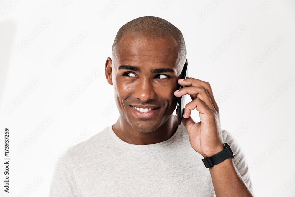 Smiling african man talking by smartphone and looking away Smiling african man talking by smartphone and looking away