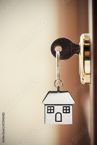 House key on a house shaped silver keyring in the lock of a door