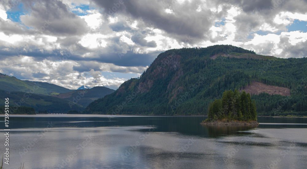 Fototapeta premium Snow capped peak in the distance against a still lake.