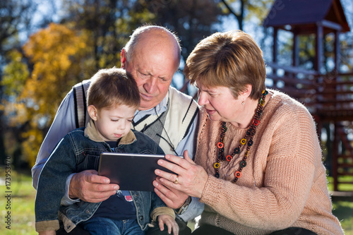 grandparents and grandson with tablet in a park in autumn © dobok
