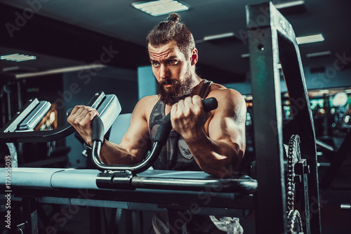 Bearded Man Doing Heavy Weight Exercise For Biceps On Machine In A Gym photo