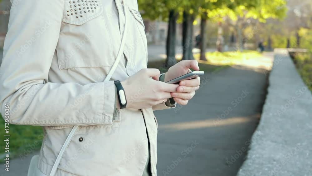 Girl in beige jacket using a mobile phone in the park Girl in beige jacket using a mobile phone in the park