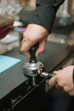 Barista pulling coffee at metal holder for espresso making.