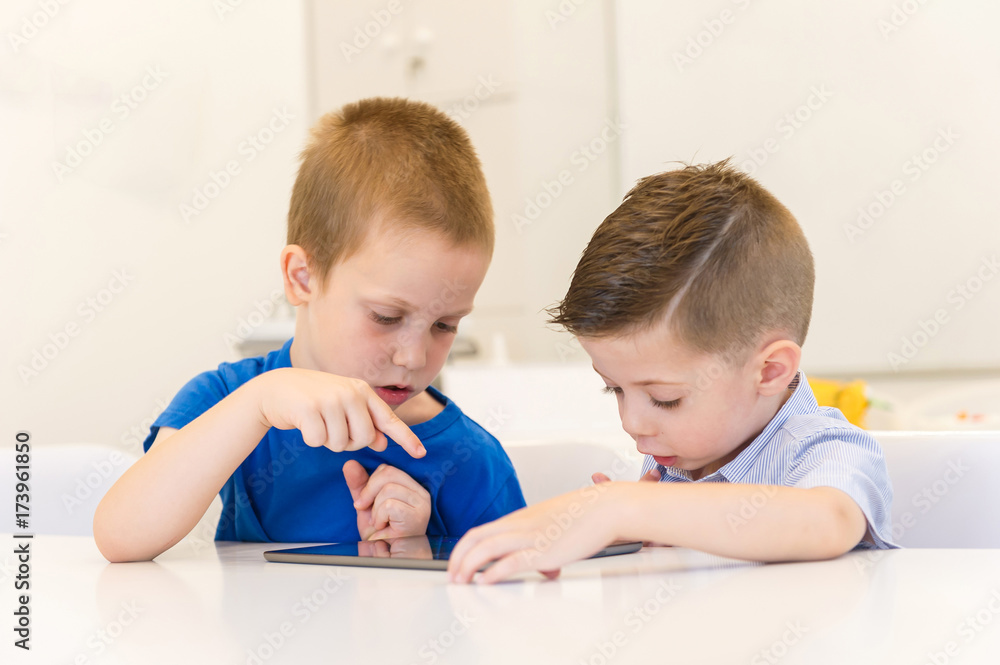 two preschooler boy using tablet on a desk two preschooler boy using tablet on a desk