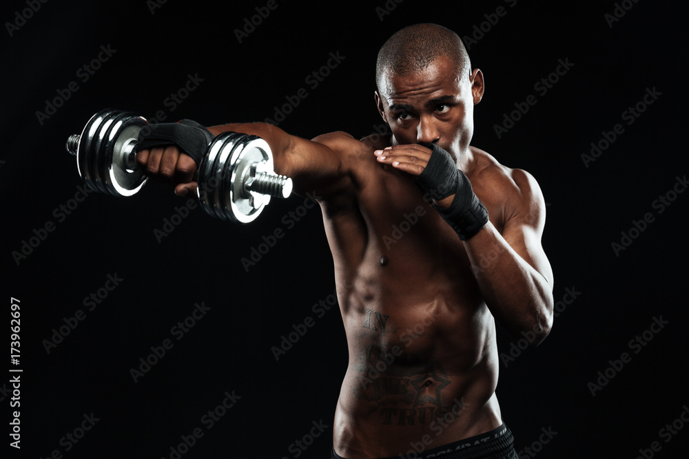 Afroamerican sports man posing like a fight with dumbbells