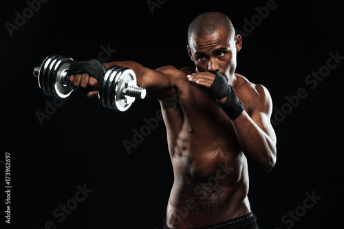 Afroamerican sports man posing like a fight with dumbbells