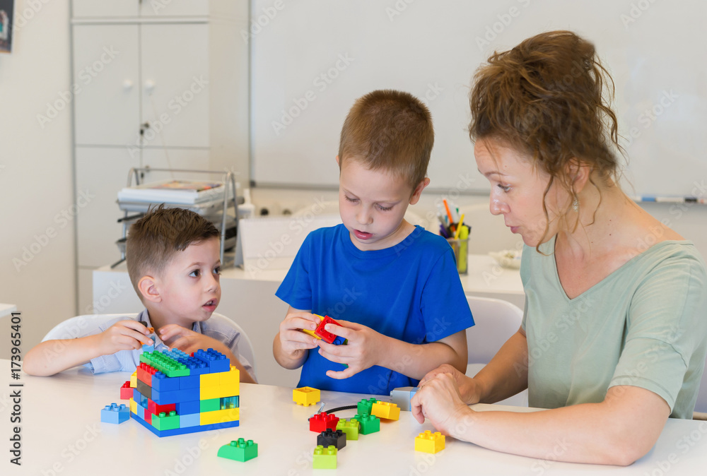 teacher woman play with two child boy with cubes in the kindergarten teacher woman play with two child boy with cubes in the kindergarten