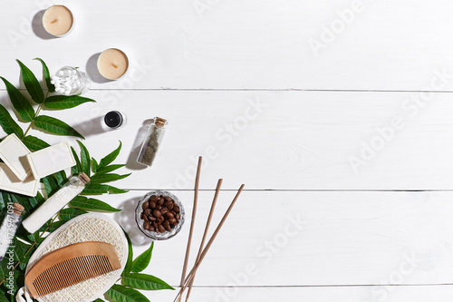 Natural handmade soaps with coffee beans, sea salt, loofah, brown towel and green leaves on white wooden background