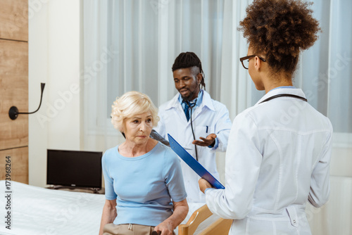 Elderly woman with doctors in hospital