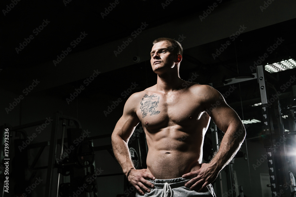 Strong man with tatoo working in gym 