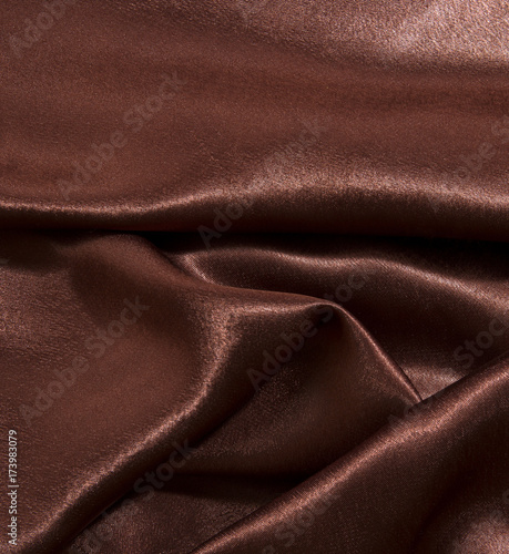 A sample of a shiny brown fabric, draped in folds.
