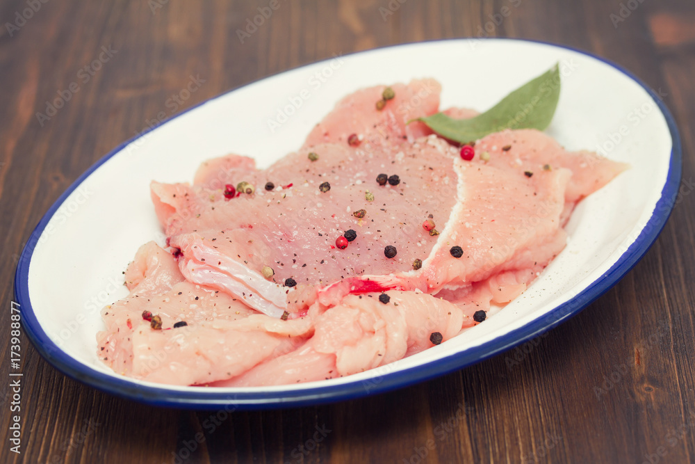 raw turkey with pepper and bay leaf on white dish raw turkey with pepper and bay leaf on white dish