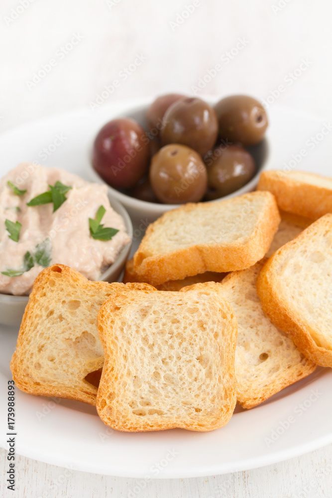 toasts with fish pate and olives on white plate toasts with fish pate and olives on white plate