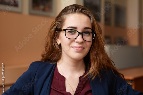 Close-up portrait of a young woman in glasses. A girl with red hair in the classroom. Business woman in training class