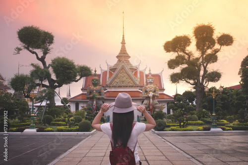 Woman in hat and red bag travel at the Wat Arun famous temple in Bangkok, Thailand. © structuresxx