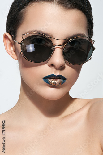seductive woman in sunglasses posing against white background