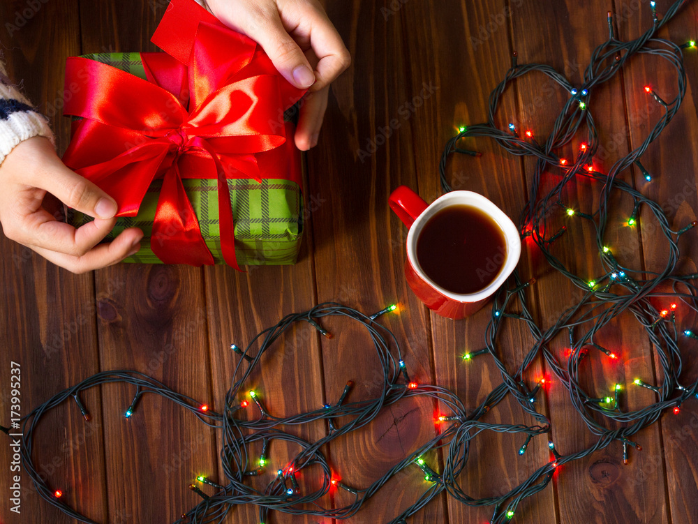 New Year's table with gifts on a wooden background. Female hands on the table New Year's table with gifts on a wooden background. Female hands on the table