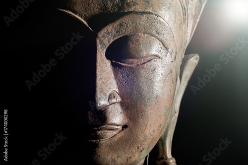 Spiritual enlightenment. Buddha head with divine light. Bronze statue face in close up. photo