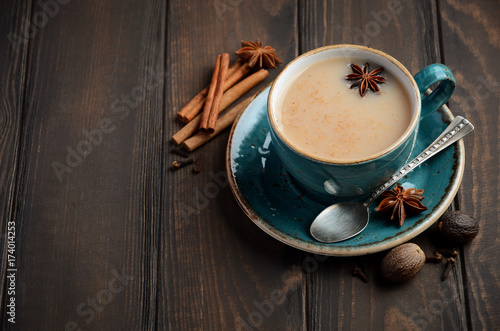 Indian masala chai tea. Spiced tea with milk on dark wooden background, copy space.