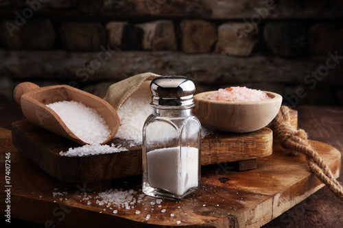 Salt Shaker and salt on wooden table. photo
