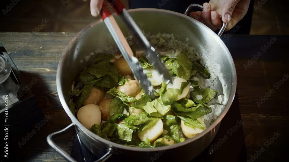 Close-up shot of the cook roasting potatoes, onions, and basil in a saucepan. 4K Close-up shot of the cook roasting potatoes, onions, and basil in a saucepan. 4K