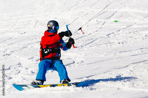 Snowboarder with a kite on fresh snow in the winter in the tundra of Russia against a clear blue sky. Teriberka, Kola Peninsula, Russia. Concept of winter sports snowkite.