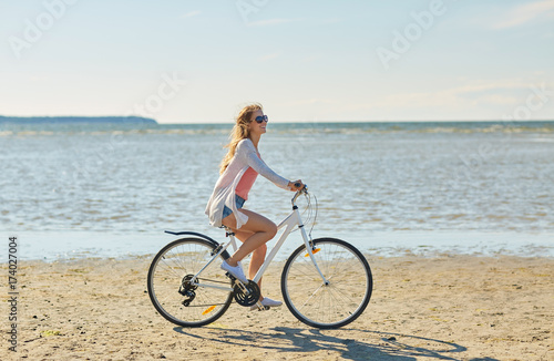 happy woman riding bicycle along summer beach