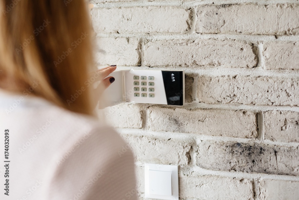 Woman entering password on home alarm keypad.