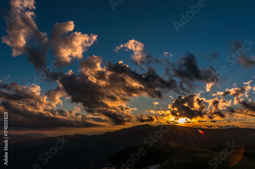 Sun setting between mountains and clouds, Veneto, Italy