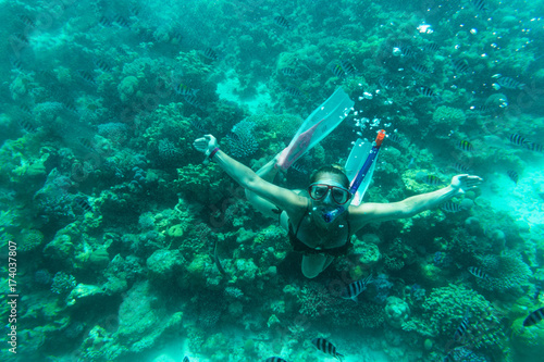 The girl floats under water on coral reefs
