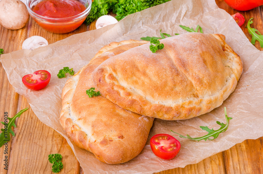 Pizza Calzone with tomato sauce, cheese, herbs, mushrooms and sausages