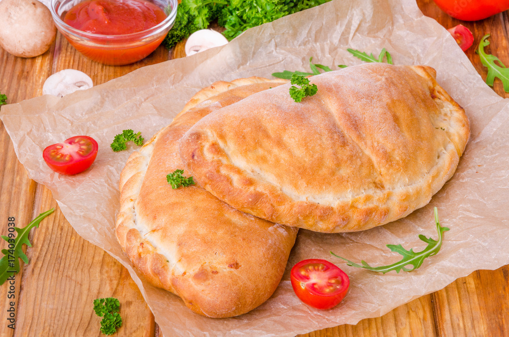 Pizza Calzone with tomato sauce, cheese, herbs, mushrooms and sausages Pizza Calzone with tomato sauce, cheese, herbs, mushrooms and sausages